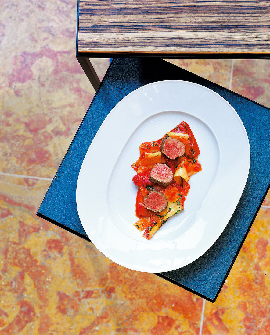 Lamb in salt crust with peppers and pasta tatters on plate