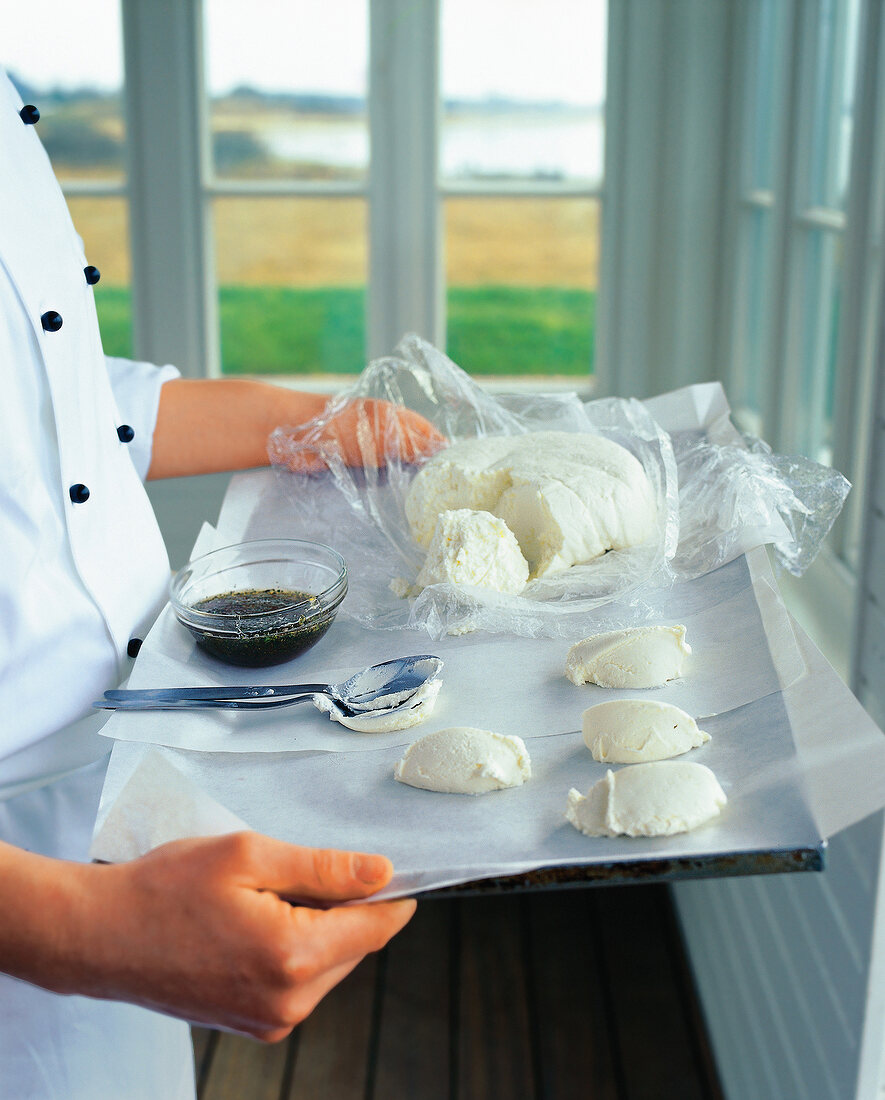 Woman's hand holding tray with goat cheese