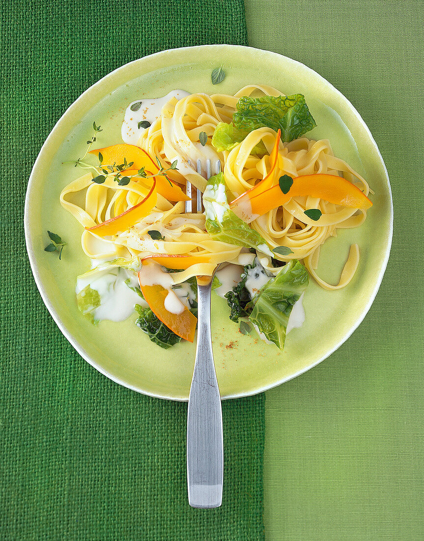Close-up of tagliatelle with savoy cabbage and pumpkin sauce in bowl, overhead view