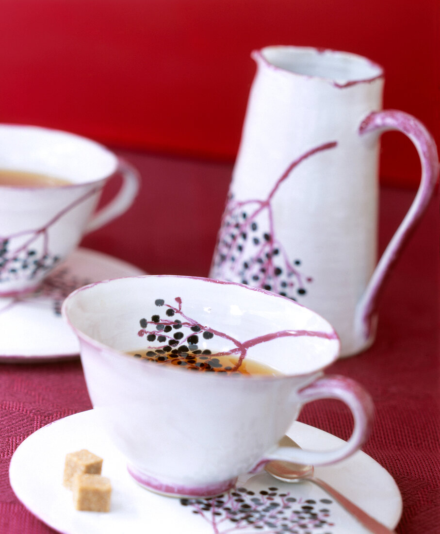 Close-up of teacup and teapot with elder scene