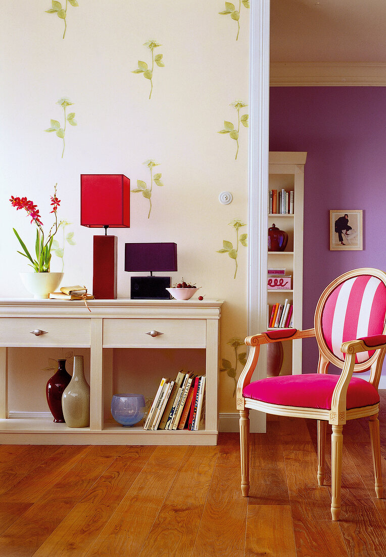 Room with sideboard, wooden floor, pink chair and floral pattern wallpaper