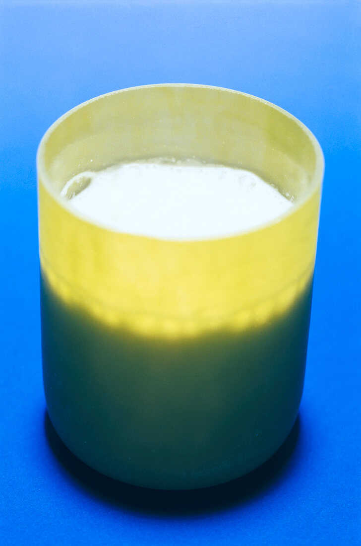 Close-up of milk shake in green glass on blue background
