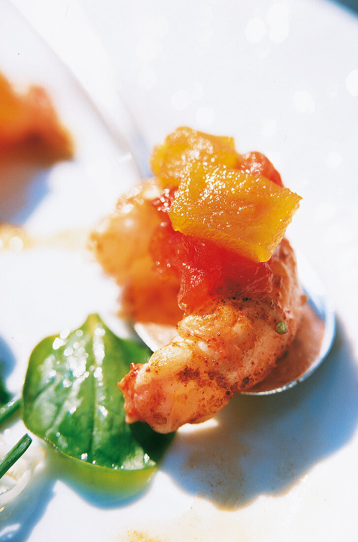 Close-up of shrimp with diced vegetables and basil leaf