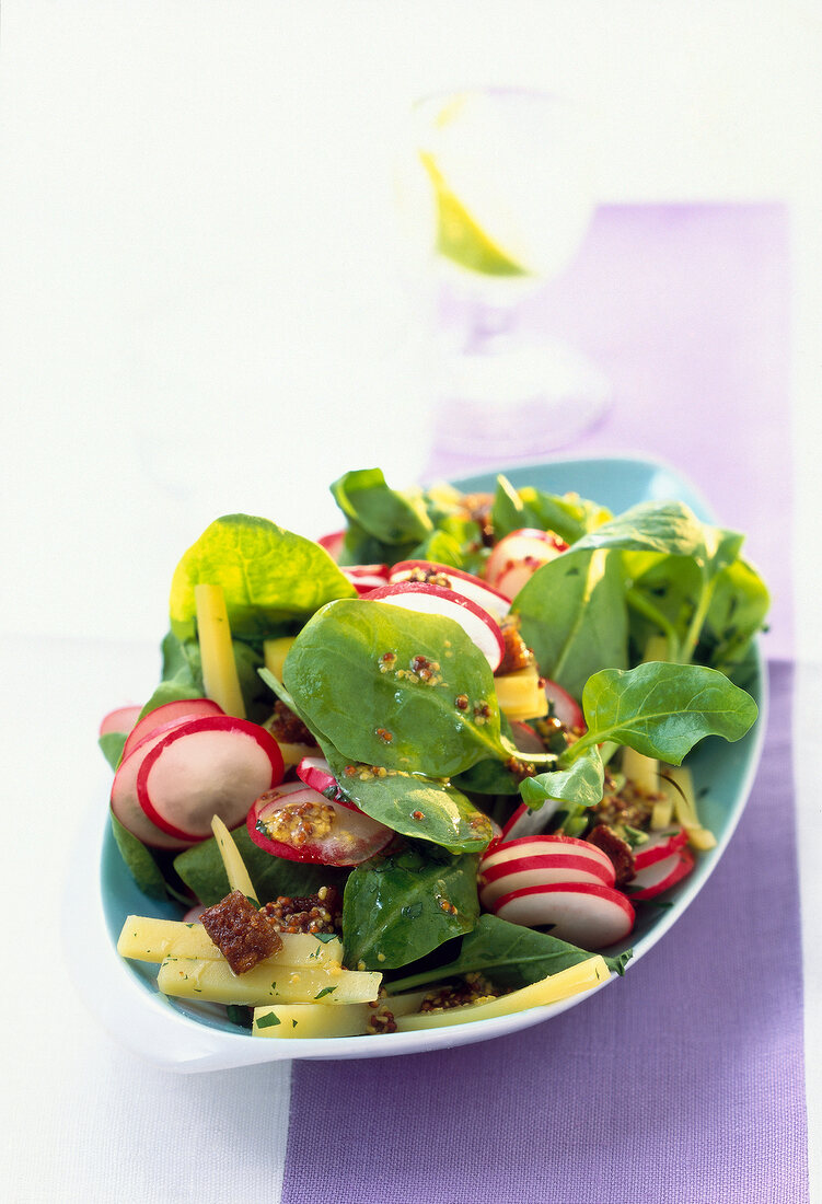 Spinach and radish salad with cheese on bowl