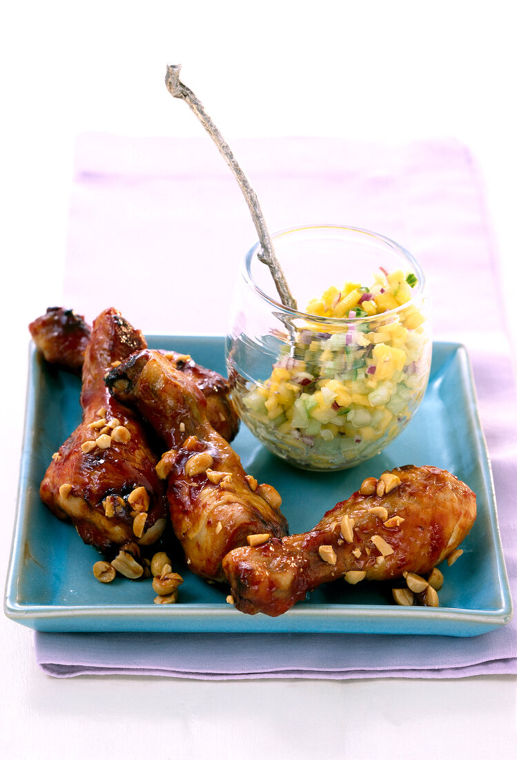 Spicy chicken legs with mango salsa on plate