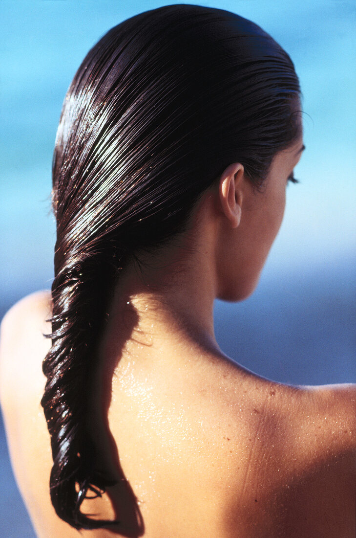 Rear view of woman applying conditioner after sunbathing