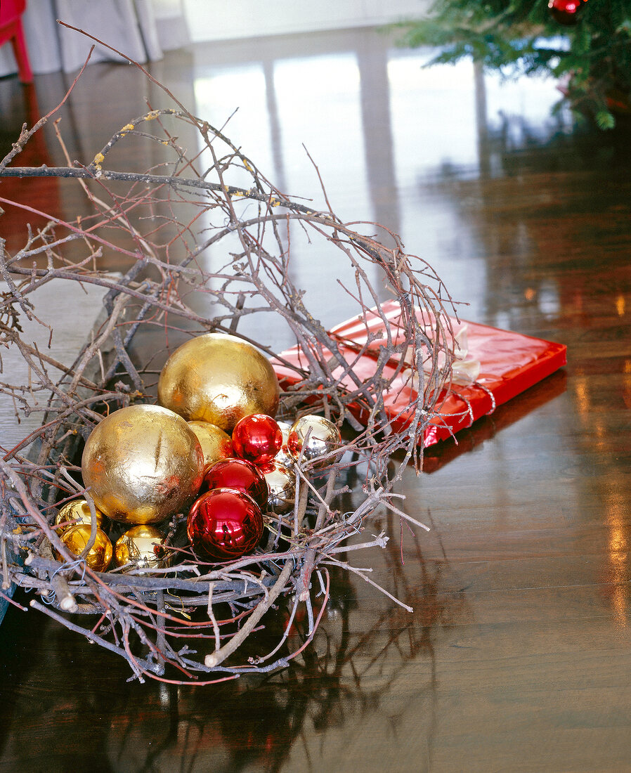 Rote und goldene Weihnachtskugeln in einem Nest aus Zweigen