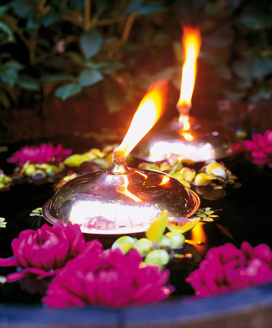 Lit lamps and flowers floating in water at balcony