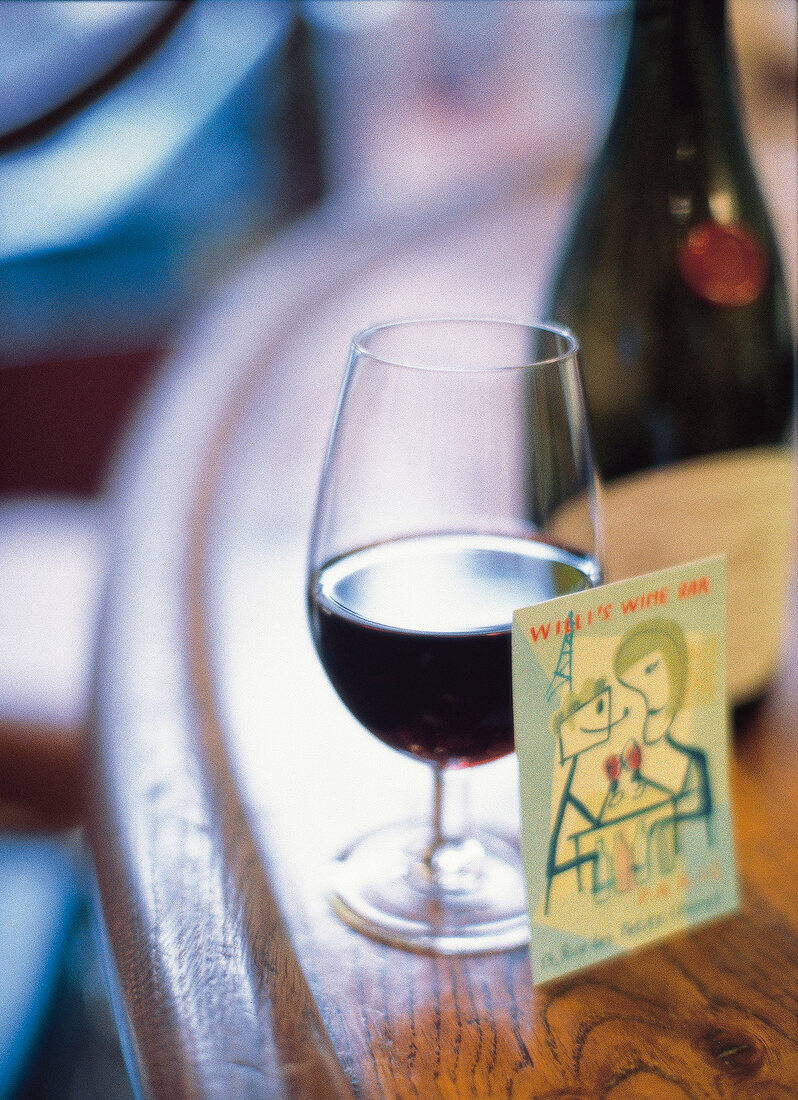 Halbgefülltes Rotweinglas mit Kärtchen, Stillleben
