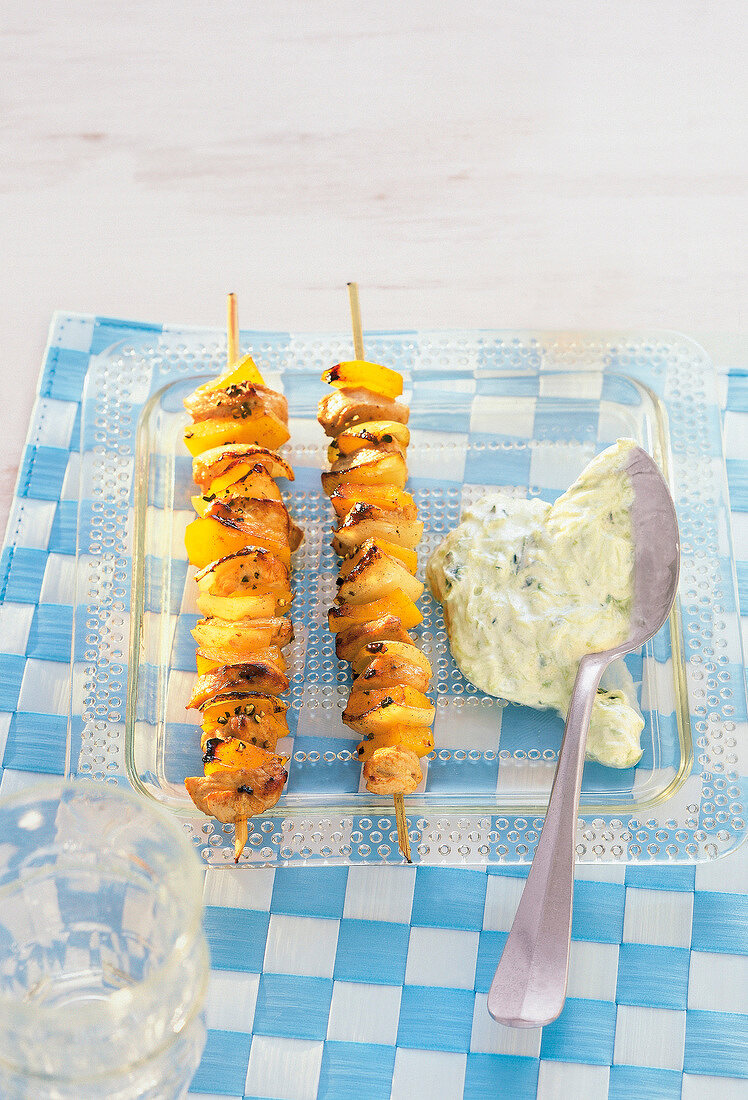 Skewers with tzatziki sauce on glass plate