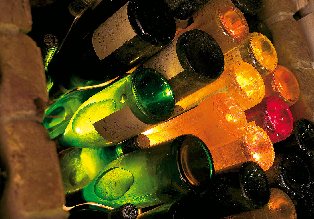 Illuminated green and white wine bottles stuck in wine rack