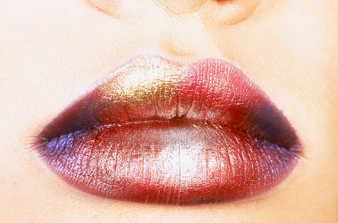 Close-up of woman's lips wearing multi-coloured shiny lipstick