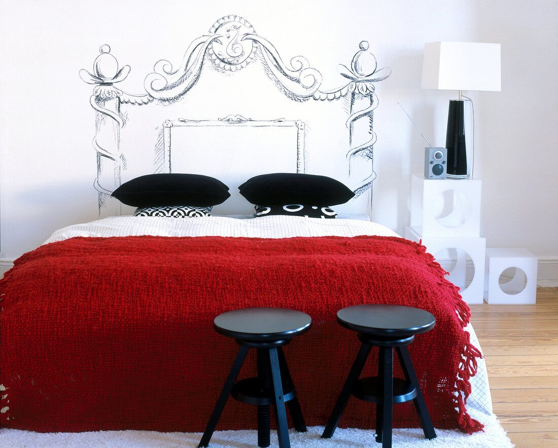 Schlafzimmer, bemaltes Kopfende hinter Bett, rote Überdecke, Hocker