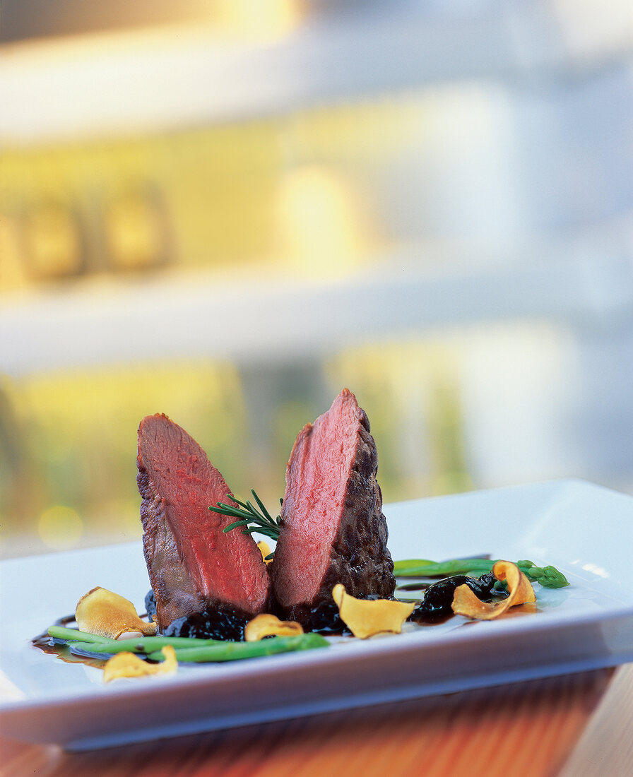 Close-up of venison medallions with balsamic plum and artichoke chips on plate