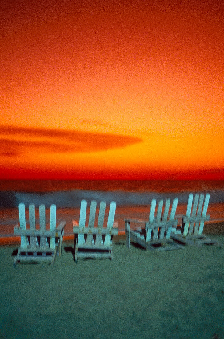 Sunset view at beach Acapulco with wooden deckchairs on beach