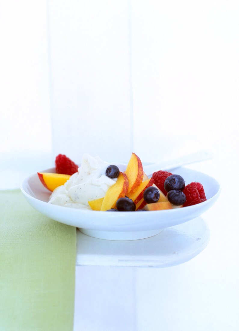 Obstsalat mit Vanillecreme zum Frühstück auf einem Teller