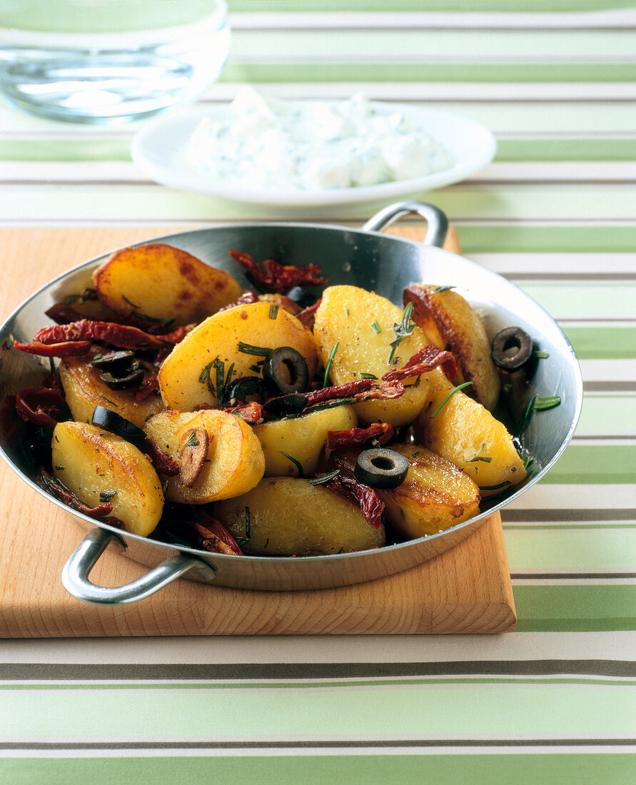 Potato, black olive and dried tomatoes in cooking pan
