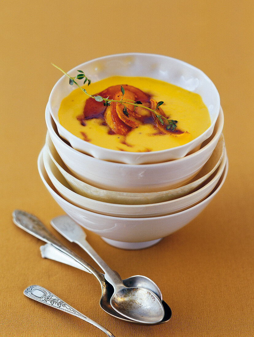 Pumpkin soup with honey and apple slices in bowl