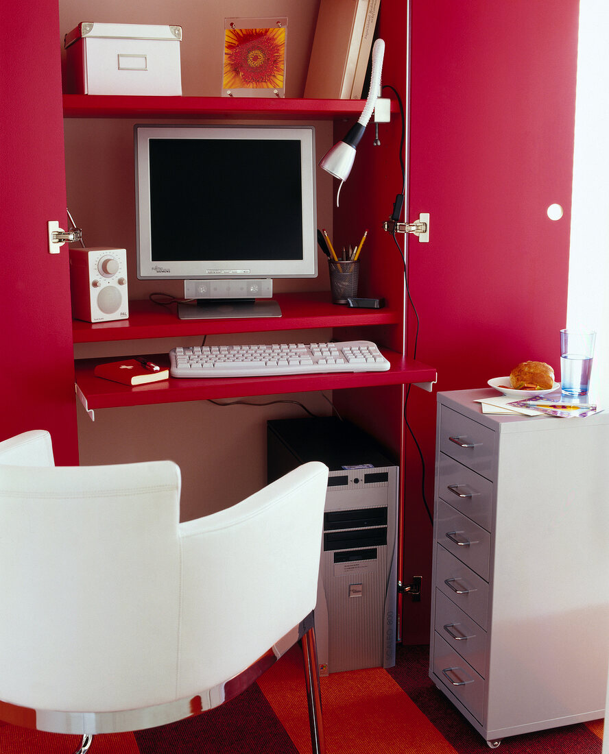 Computers in hall closet with drawers and chair