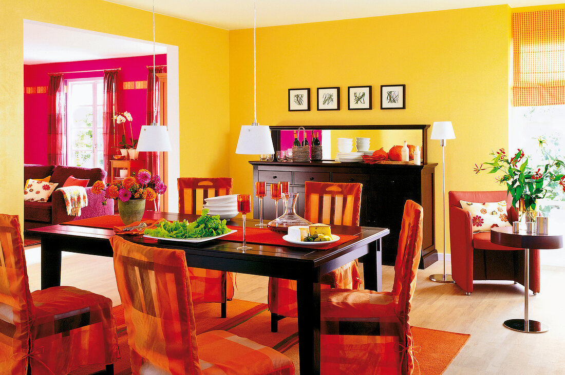 Esszimmer in Orange und Schwarz: dunkler Holztisch, Stühle mit Hussen