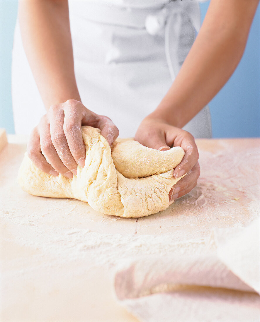 Brot selbst backen: Teig kneten mit beiden Händen auf dünner Mehlschicht