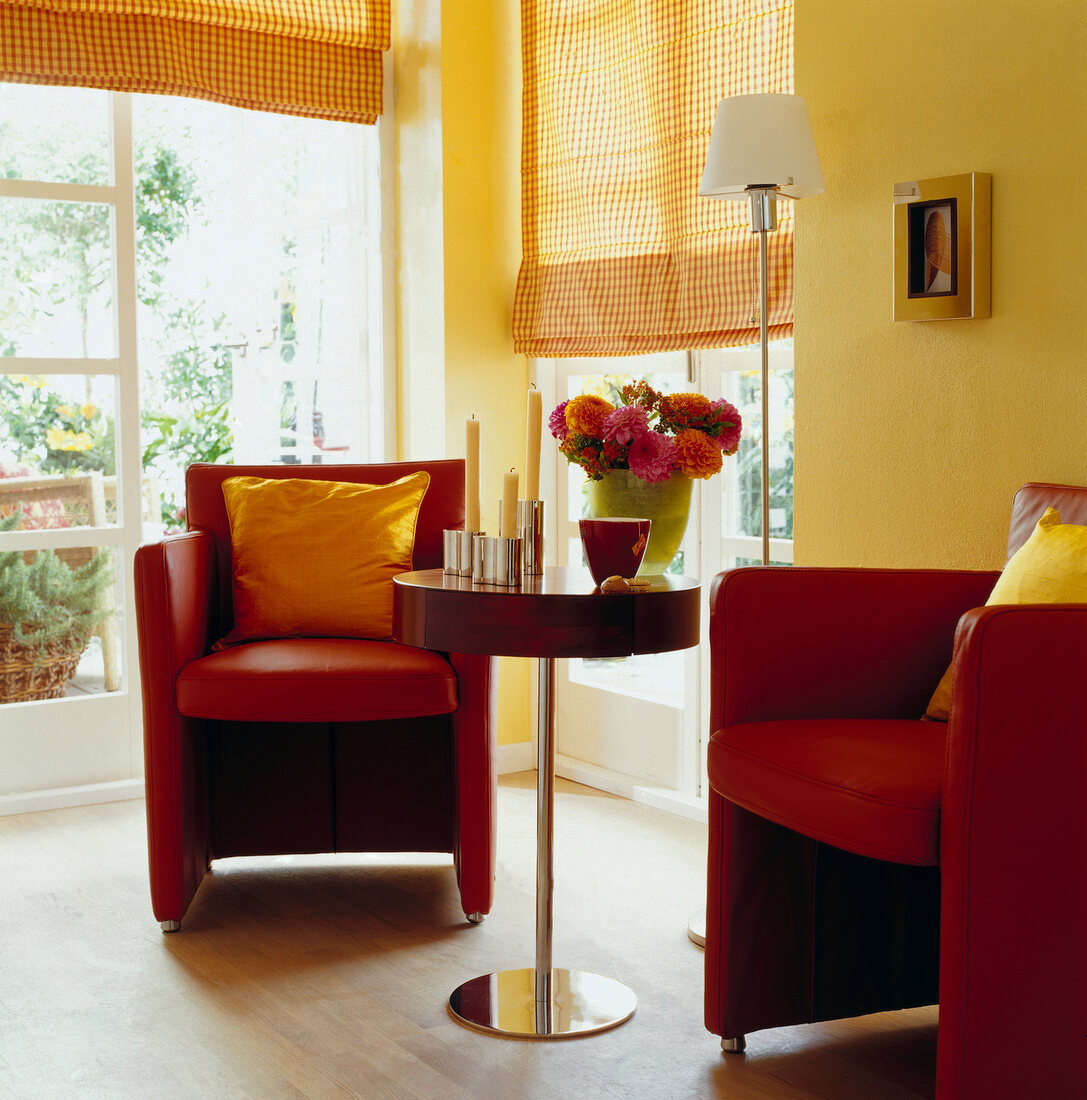 Rote Sessel mit gelben Kissen, rund. Beistelltisch am Fenster, Wand gelb