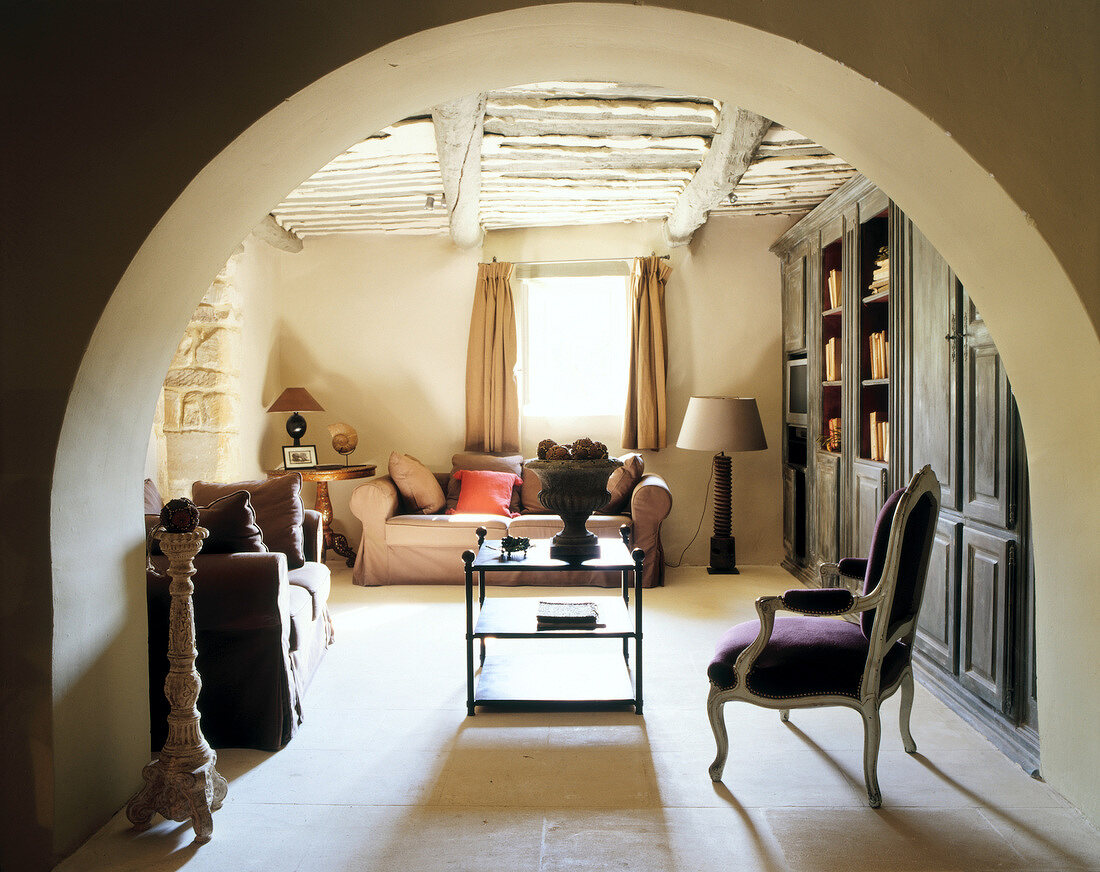 Living room with beamed ceiling and sofa in front of window, Provence, France