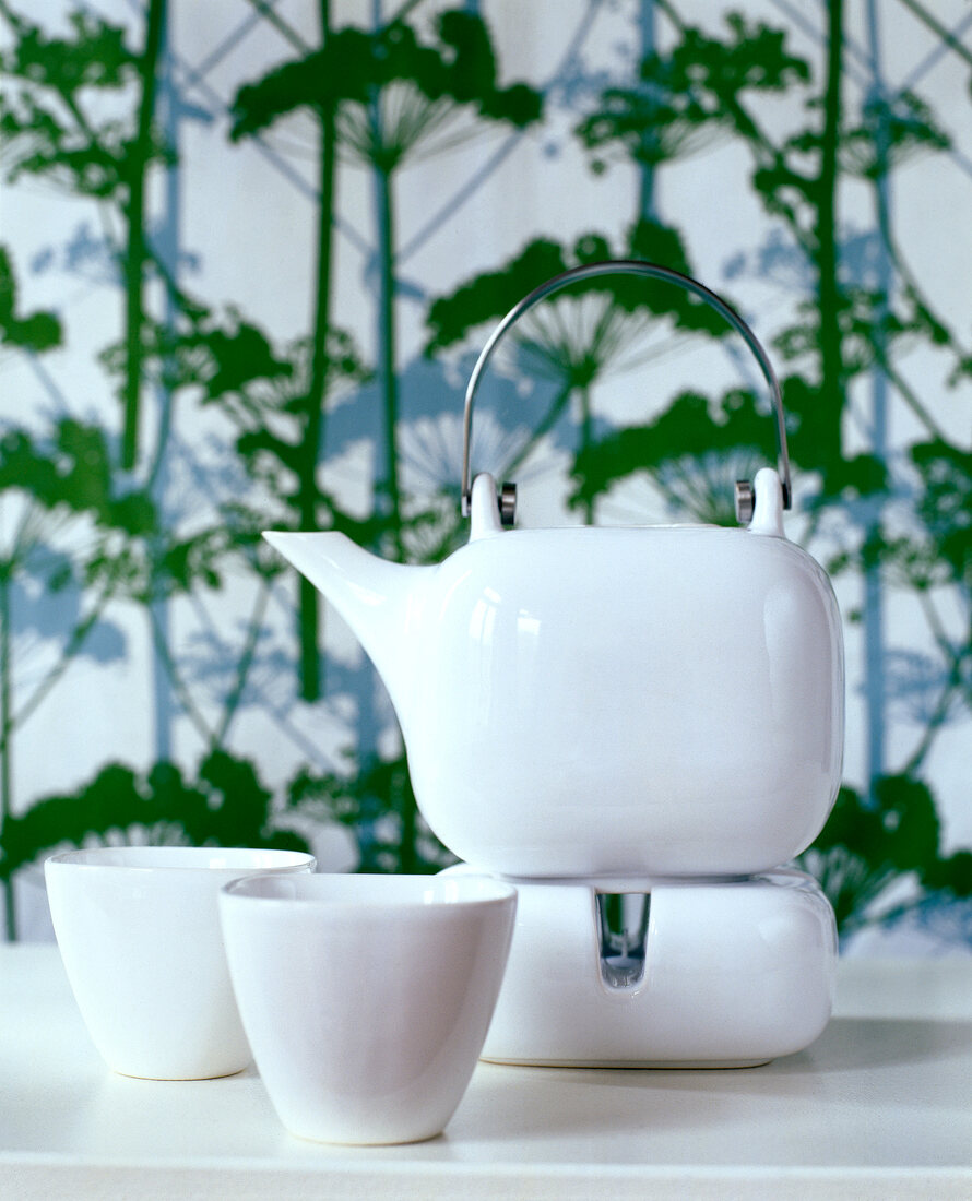 White porcelain teapot with two teacups on table