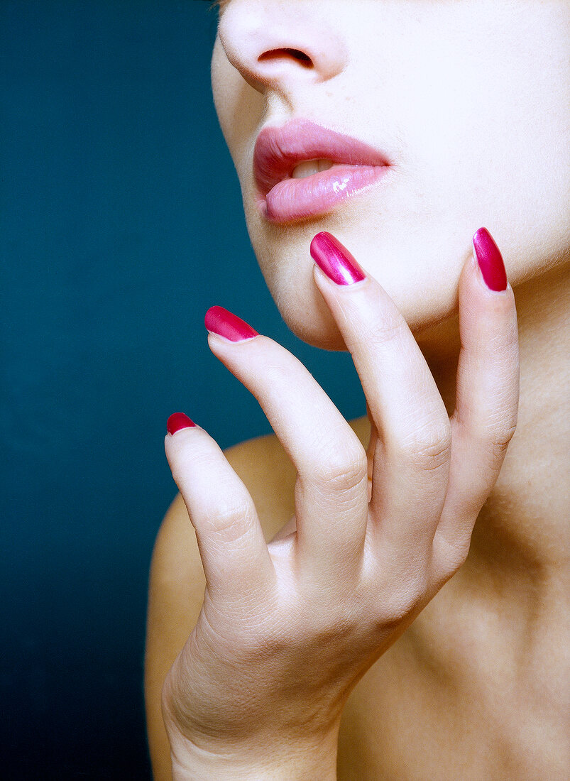 Close-up of beautiful young woman with pink lipstick and pink nail polish