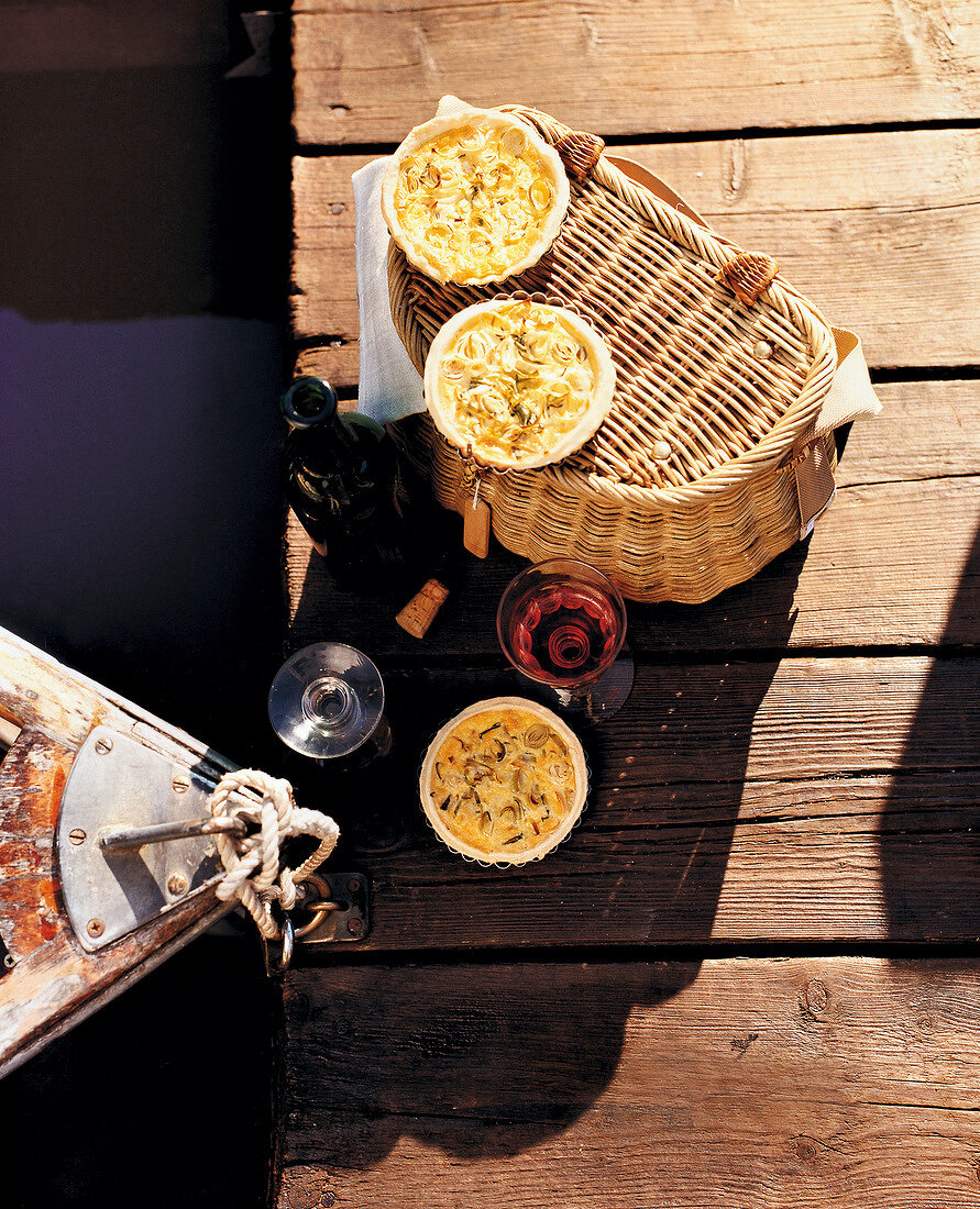 Picknick am See auf Bootssteg, Wein, Weinflasche, Quiche auf Korb