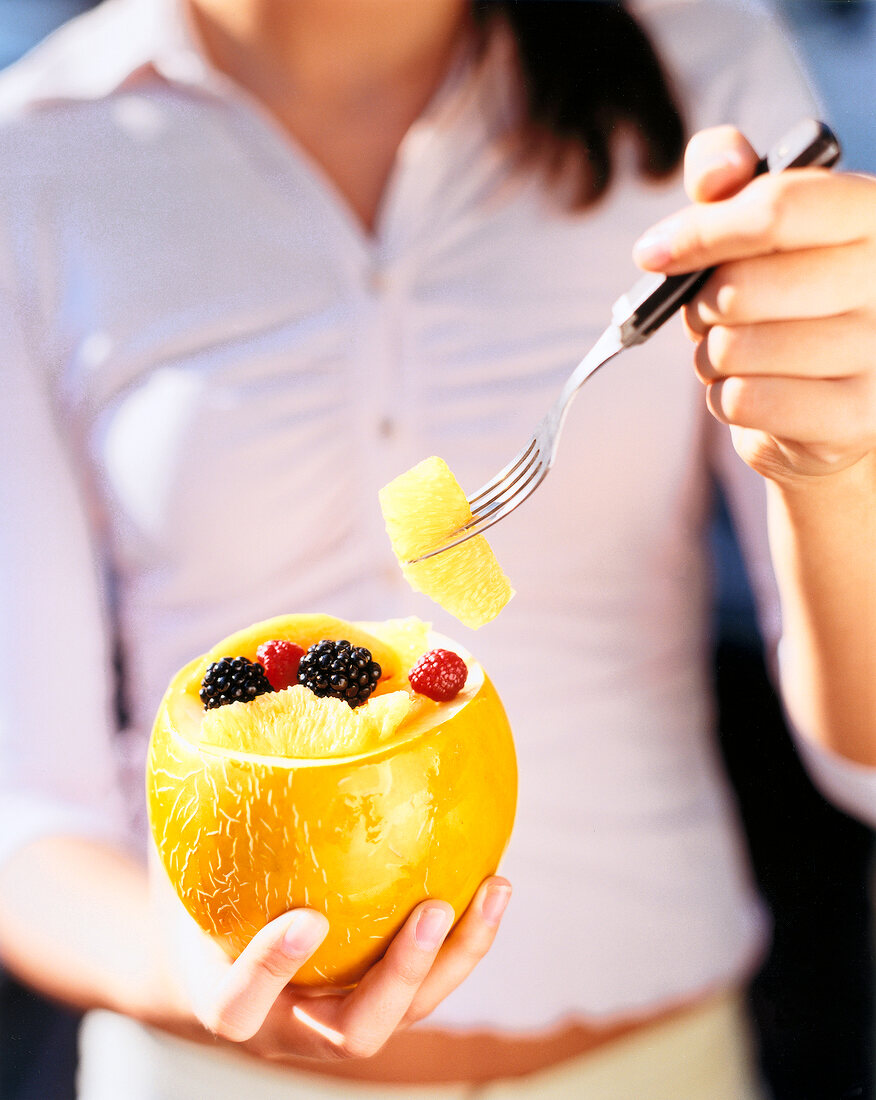 Woman having fruit salad in honeydew melon at picnic