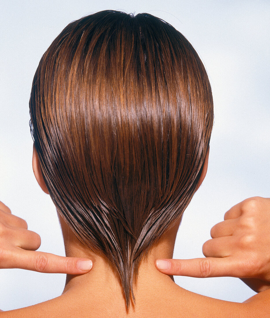 Rear view of woman with brown streaks massaging her cervical region with index fingers