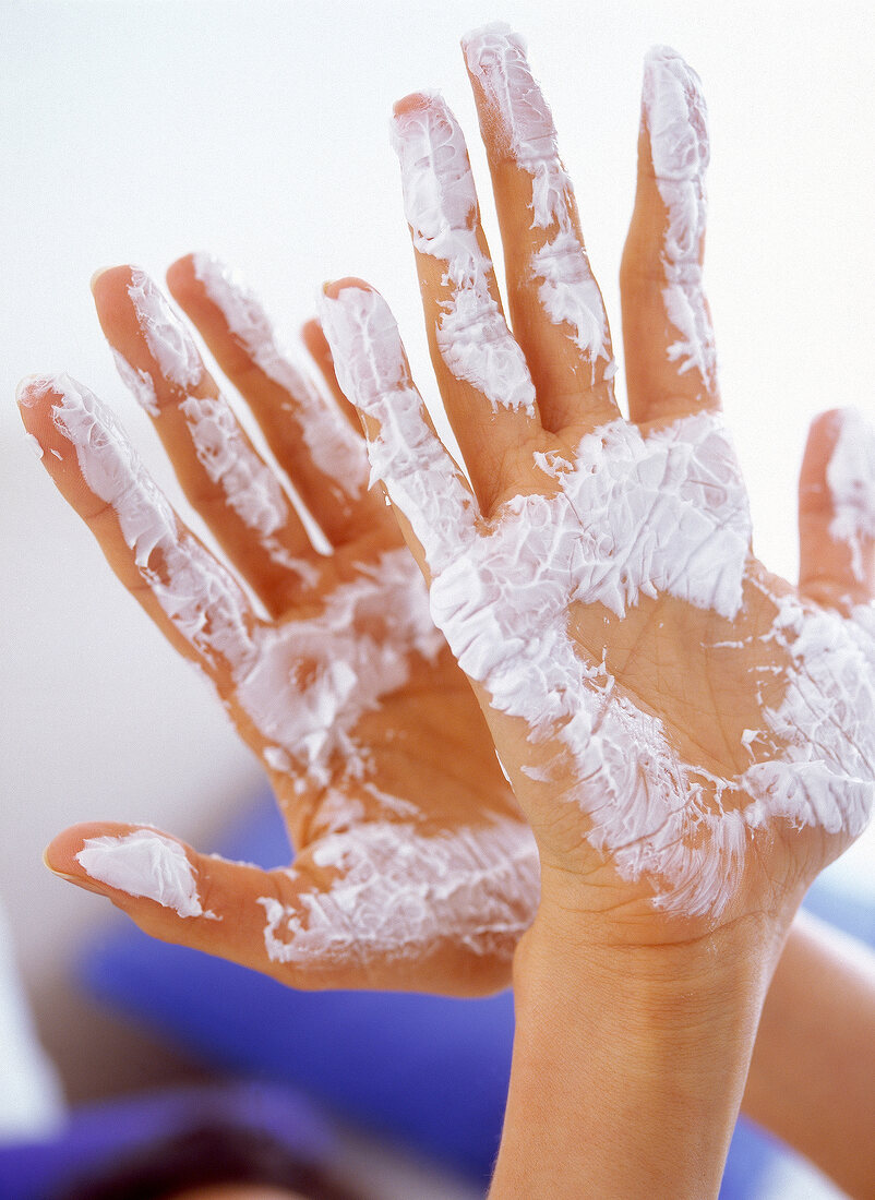 Close-up of woman's palms with white cream smeared on them