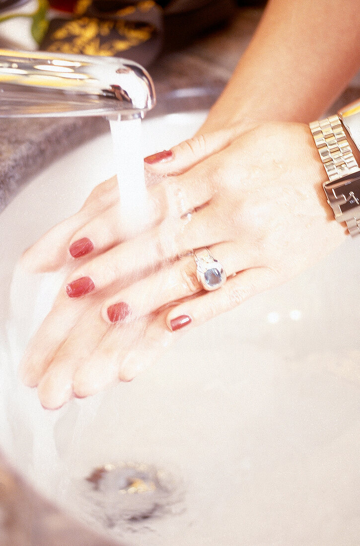 Frau mit lackierten Fingernägeln wäscht sich die Hände