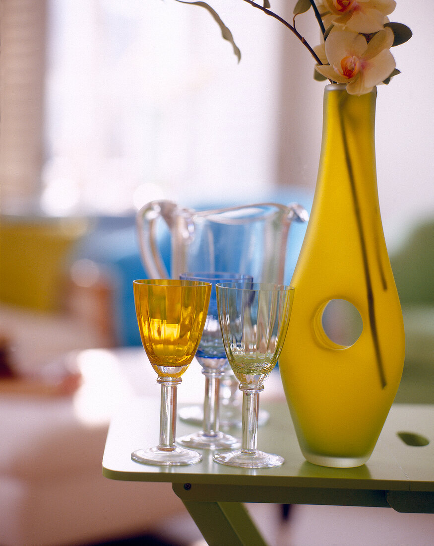 Yellow flower vase with hole and three glasses on table