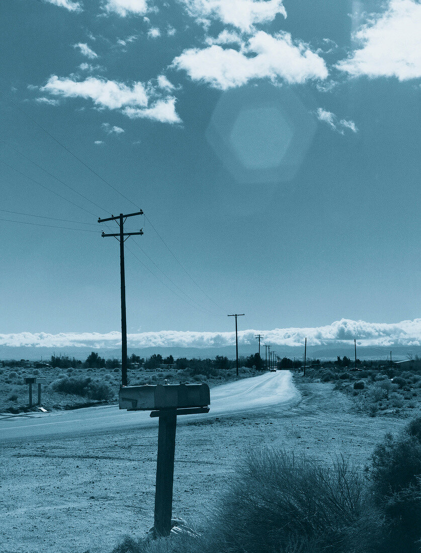 View of country road and electricity pylon on American desert landscape, USA, toned image