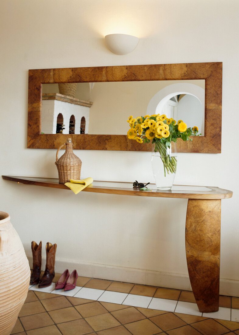 Mirror with wooden frame and wooden side table in corridor