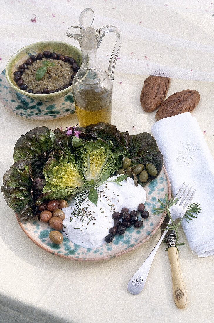 Olives, salad and cream cheese on ceramic plate