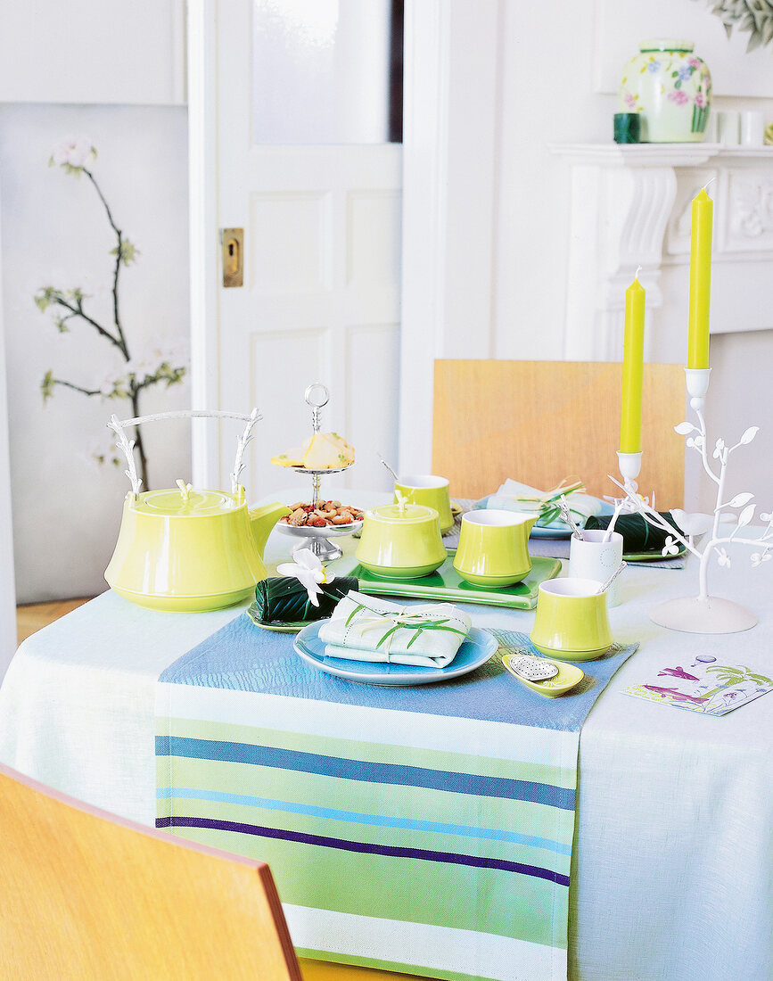 Table decorated with green tea set, candles and place mat