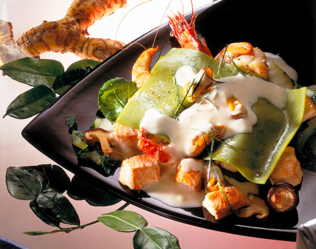 Lasagna with seafood and coconut curry sauce on black plate, Euro-Asian cuisine