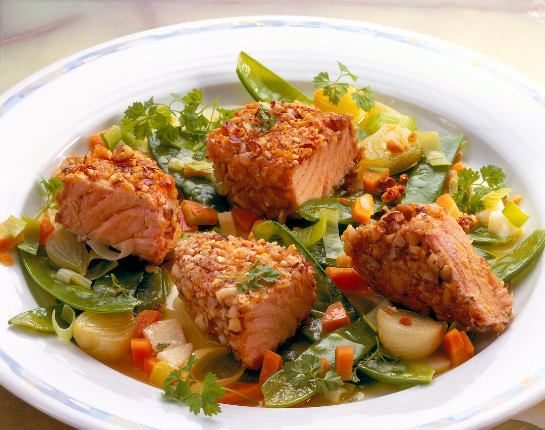 Salmon in polynuclear cover with soup vegetables and shallots on dish