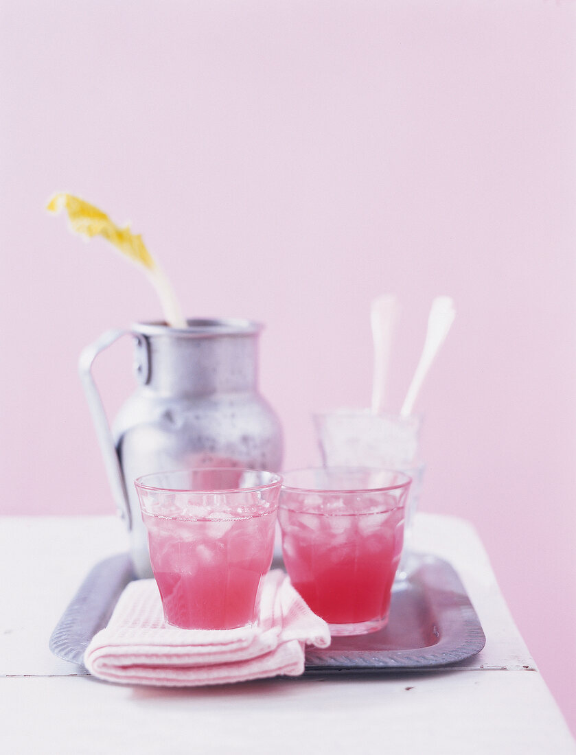 Rhubarb mallow drink with cinnamon sticks and napkin on metal tray