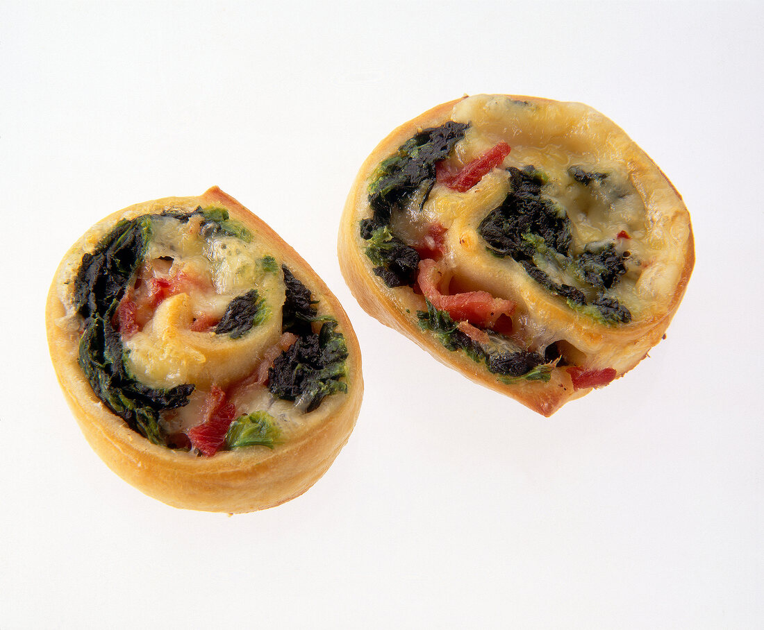 Close-up of teigschnecken pastry with spinach ham and cheese rolled on white background