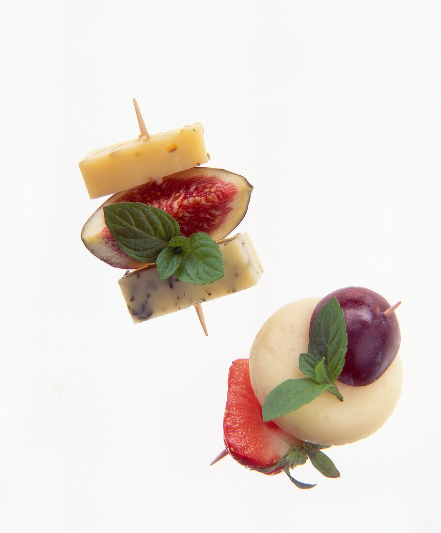 Close-up of cheese skewers with peppers, figs, berries on white background