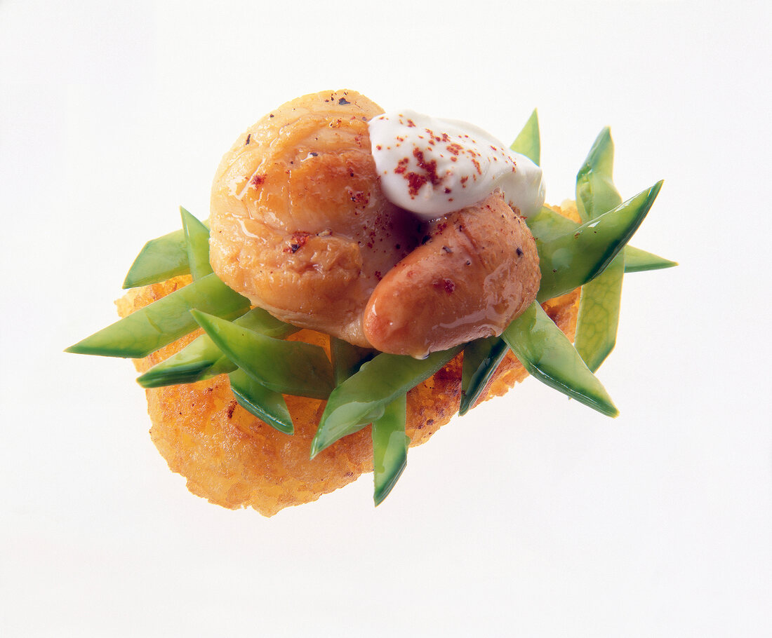 Close-up of hash browns with mussels, peas, fresh cream on white background