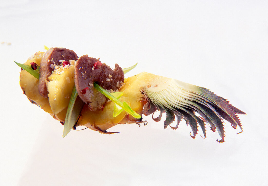 Close-up of ship shaped baby pineapple with pork on white background