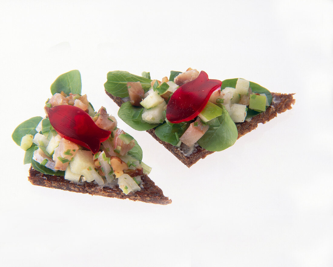 Close-up of pumpernickel with young herring pieces, cucumber, hallots and apples