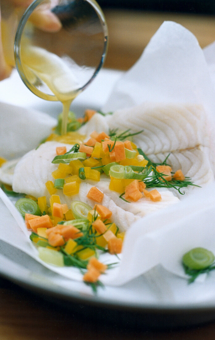 Fish in parchment with leeks and peppers on plate