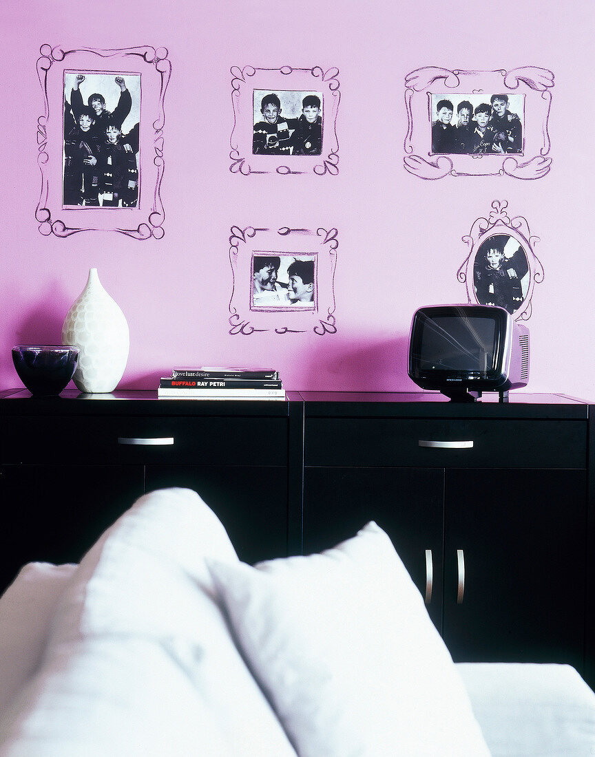 Self painted picture frames with photos on purple wall and black sideboard against it
