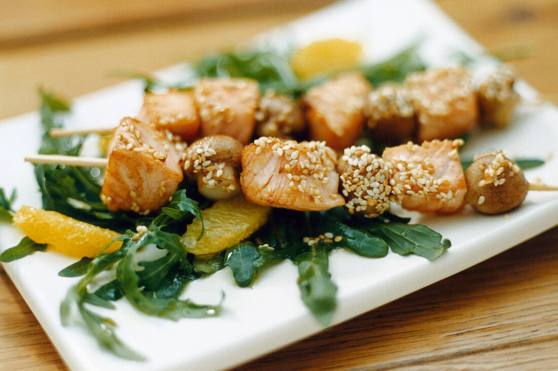 Salmon mushroom skewers with oranges and rocket salad on plate